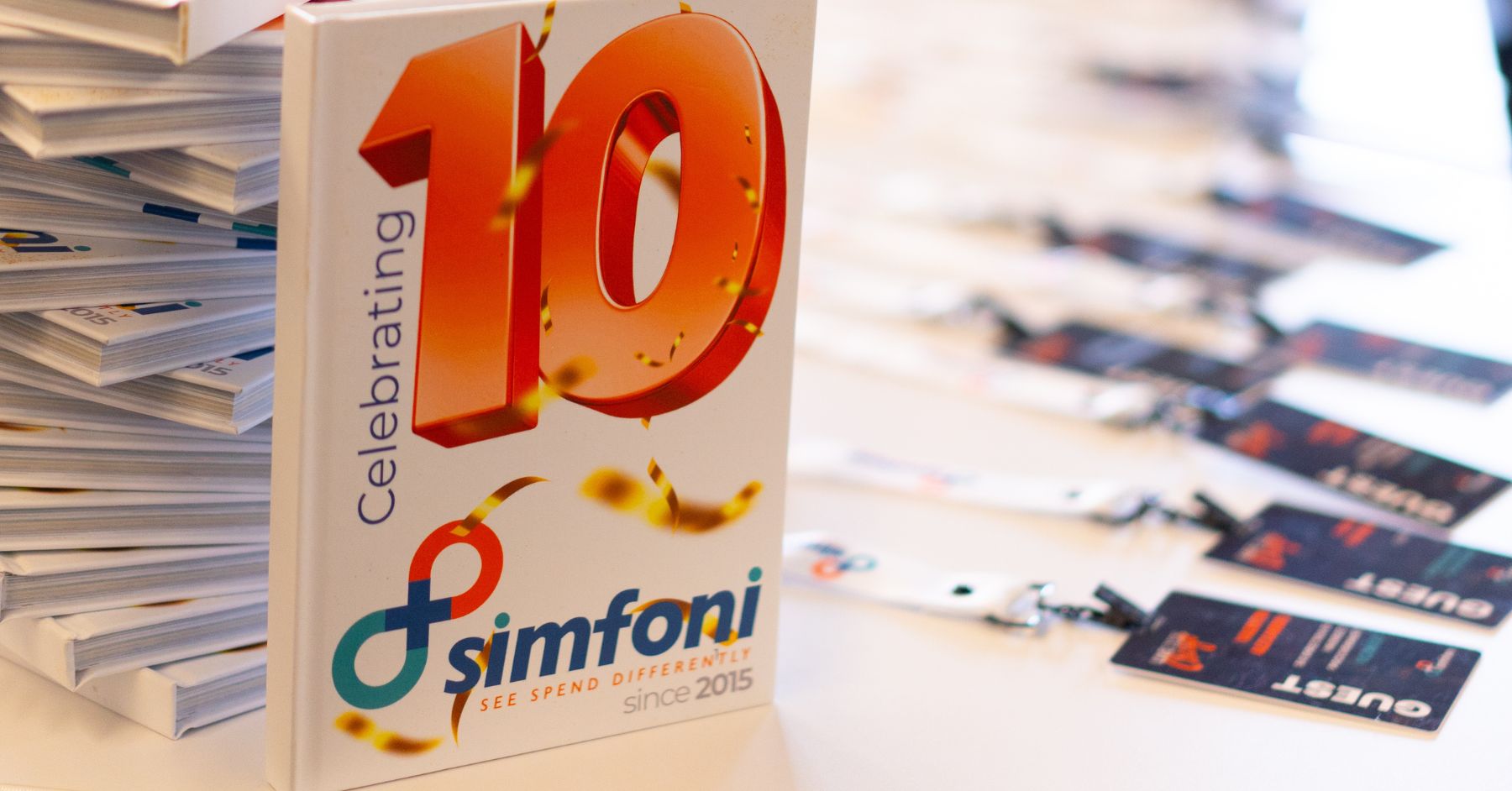 Simfoni 10-year anniversary booklet and guest badges displayed at Simfoni Live 2025 in Chicago.